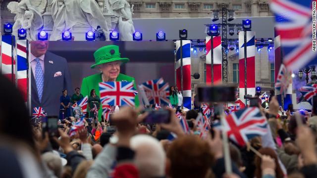 A screen in front of Buckingham Palace shows the Queen's balcony appearance on Sunday.