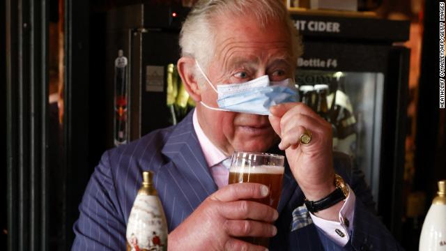 The Prince of Wales lifts his face covering to sample a pint he poured during a visit to the Prince of Wales pub in Clapham Old Town, south London on Thursday. 