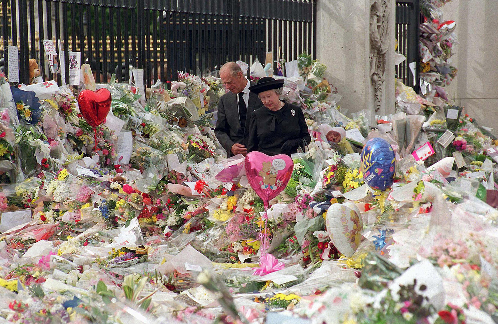 On the eve of Diana's funeral, the Queen and Prince Philip look at floral tributes left outside Buckingham Palace. 