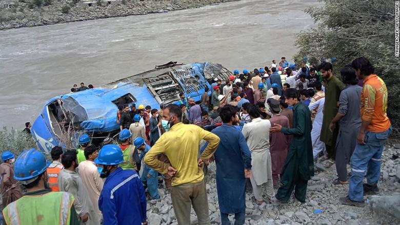 Rescue workers and onlookers gather around a wreck after a bus plunged into a ravine following an explosion in Pakistan on July 14.