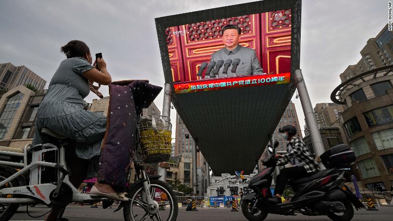 A woman watches Xi Jinping speaking during an event to commemorate the 100th anniversary of China's Communist Party at Tiananmen Square in Beijing on July 1