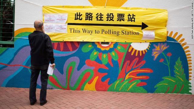 A man looks at a banner outside a polling station during the Legislative Council election.