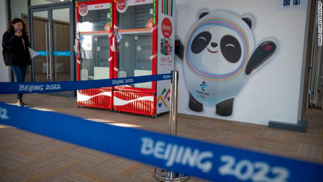 A staff member walks past a mural of the Olympic mascot and Coca Cola-branded refrigerators at the Winter Olympic Village in Beijing on December 24, 2021.