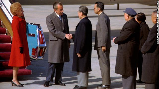 US President Richard Nixon shakes hands with Premier of the People's Republic of China Zhou Enlai after arriving in Beijing on February 21, 1972, as First Lady Pat Nixon looks on.