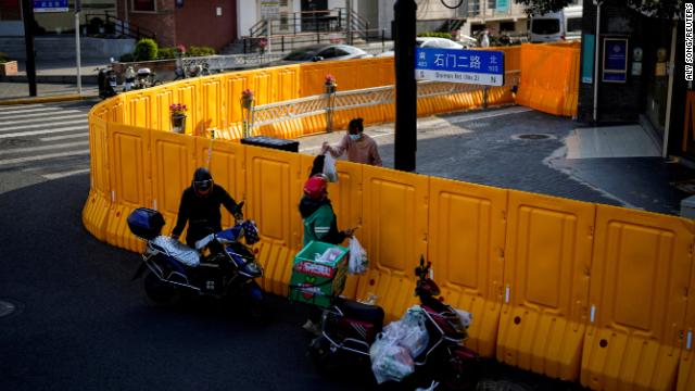 A delivery worker passes food to a resident over barriers restricting an area under lockdown in Shanghai, China, on March 23.