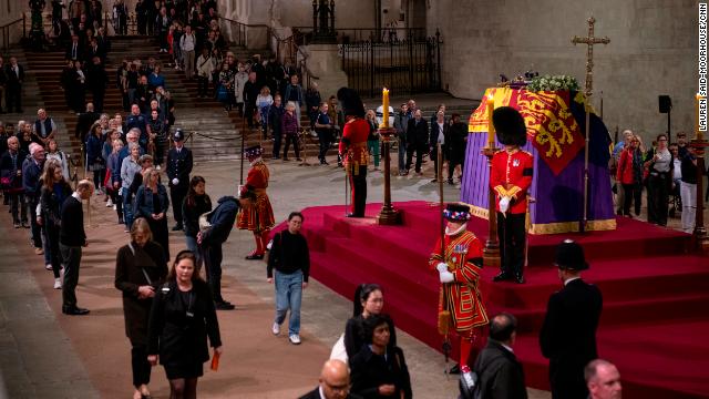 Members of the public view the Queen's coffin, which is draped with the Royal Standard, on which lie the Instruments of State -- the Imperial State Crown and the Orb and Sceptre.