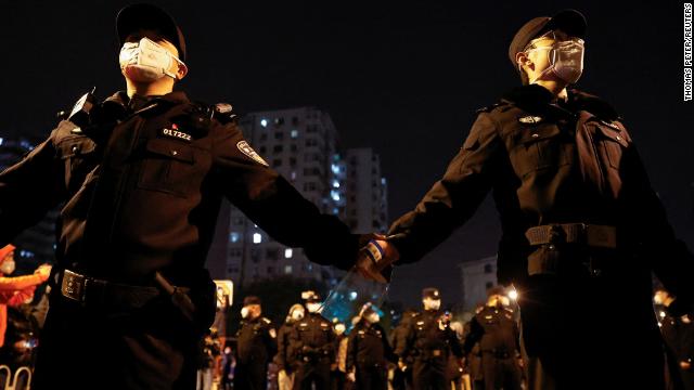 Police officers stand guard as people protest in Beijing on November 27.