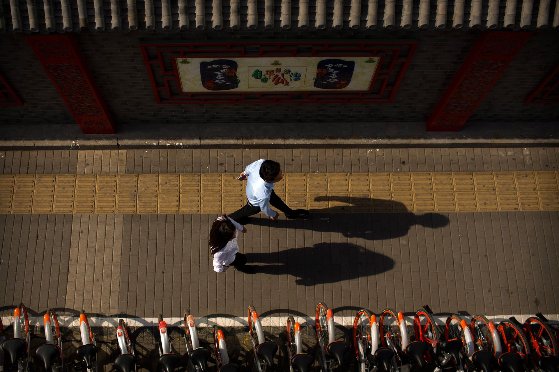 Pedestrians walk along a sidewalk in Beijing, China, on May 25, 2017.