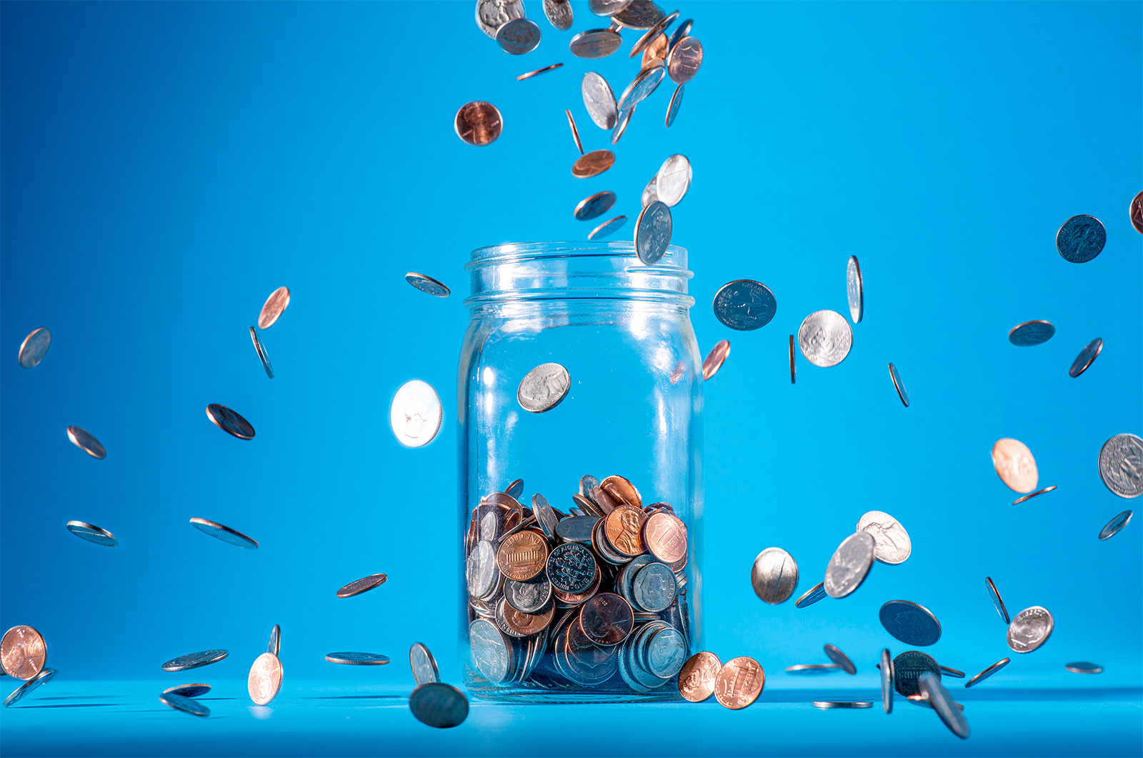 Loose change falling into an open jar