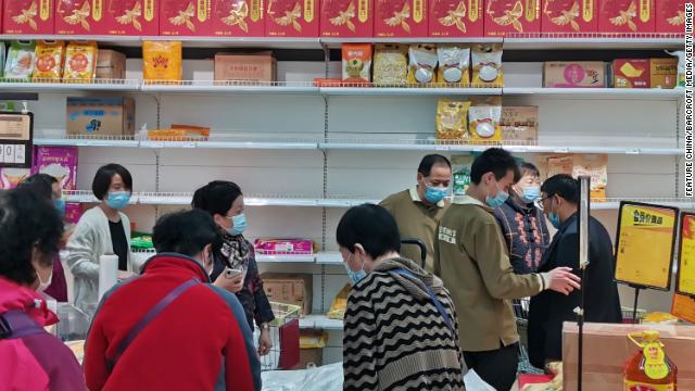 People shop beside the half-empty shelf of food in a supermarket in Zhengzhou city in central China on November 3.