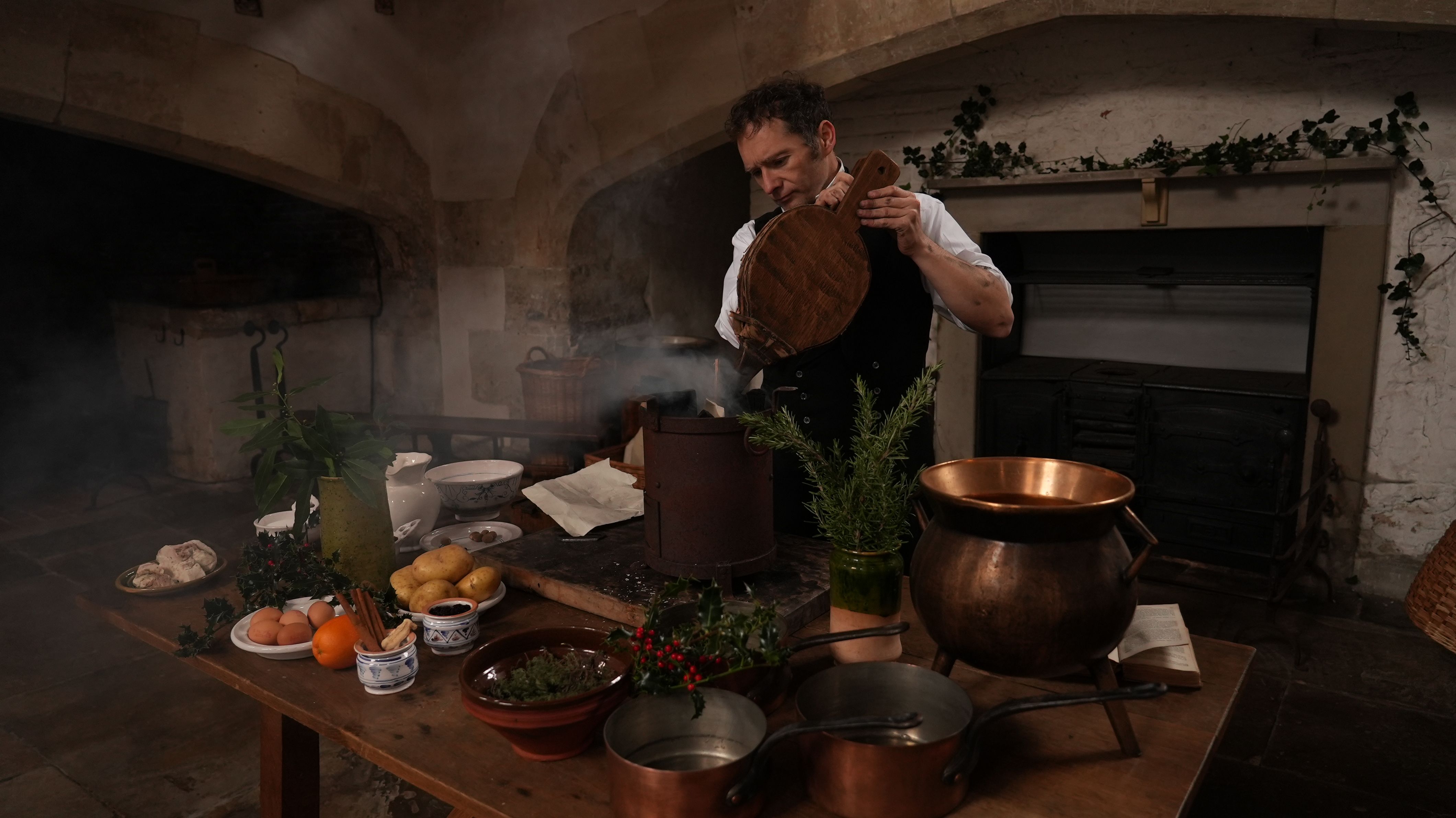 A man in Tudor costume stands behind a table of food