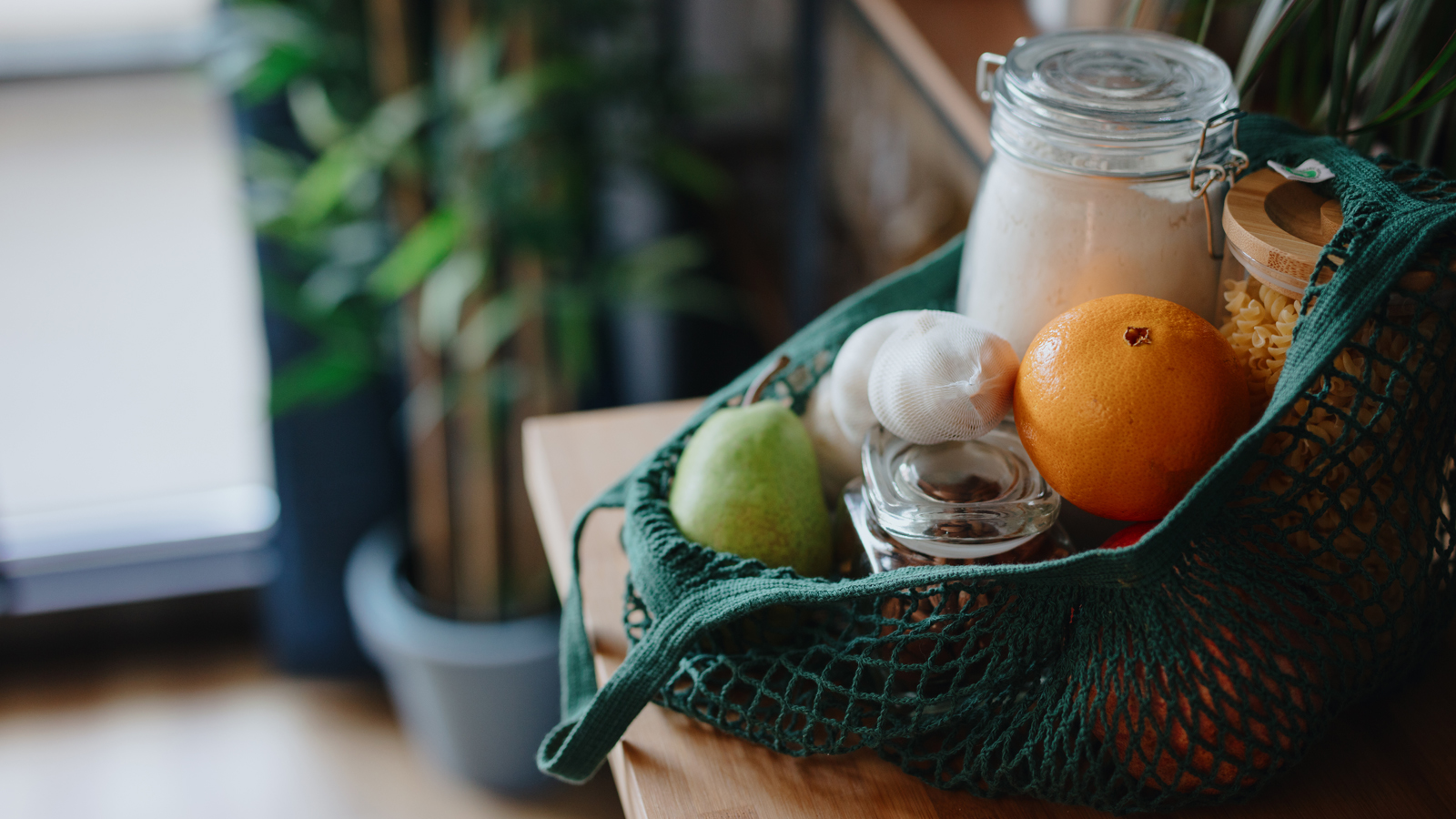 Eco bag on kitchen counter with food in jars and fresh fruits. Zero waste concept