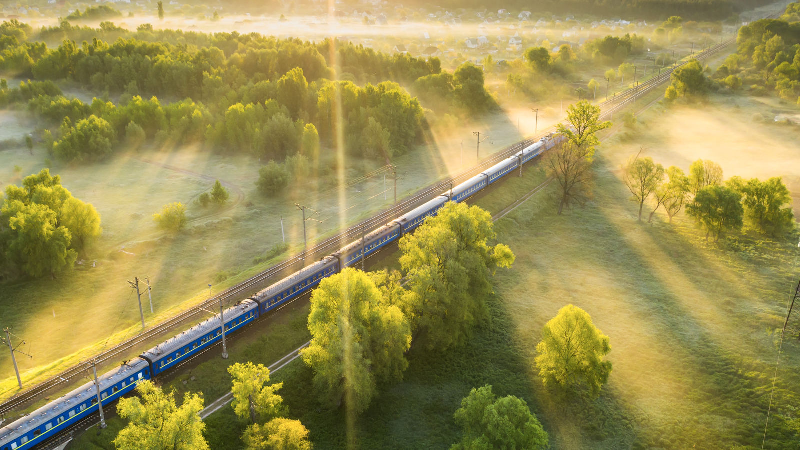 Aerial view of passenger train on the railroad in misty dawn