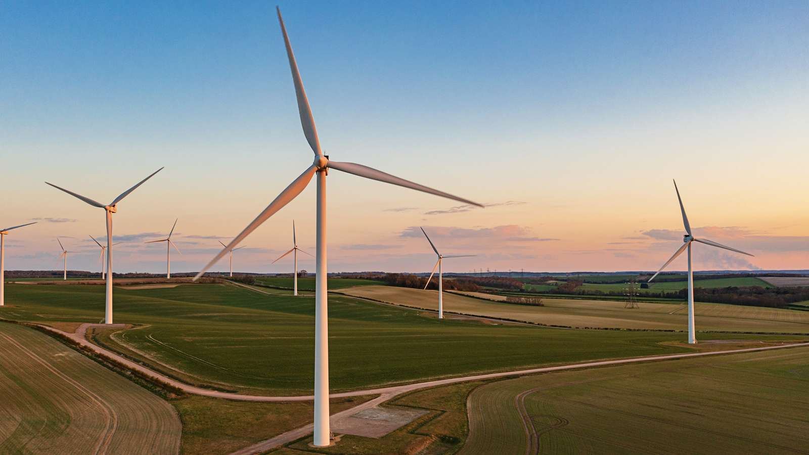 Drone view of a wind farm at sunset. Multiple wind turbines