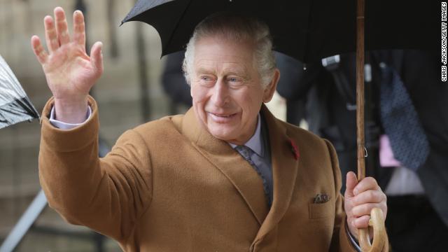 King Charles III waves to onlookers.