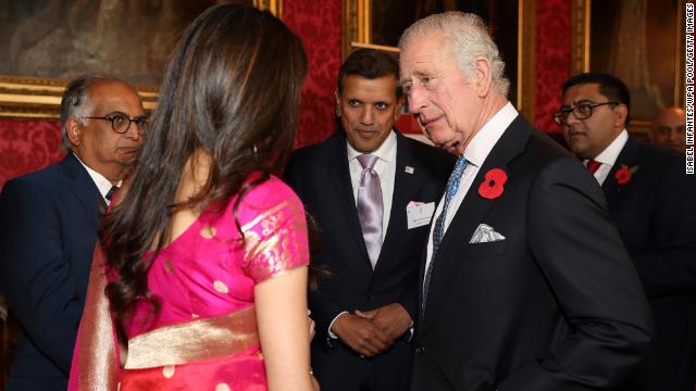 King Charles talks with guests while hosting a reception at Buckingham Palace.