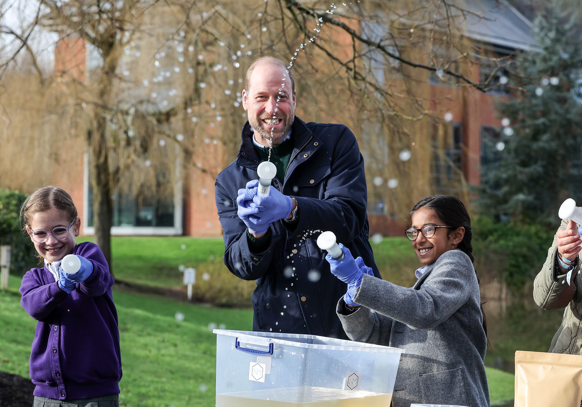 Prince William jokes around with local school children as they filter DNA samples through a syringe