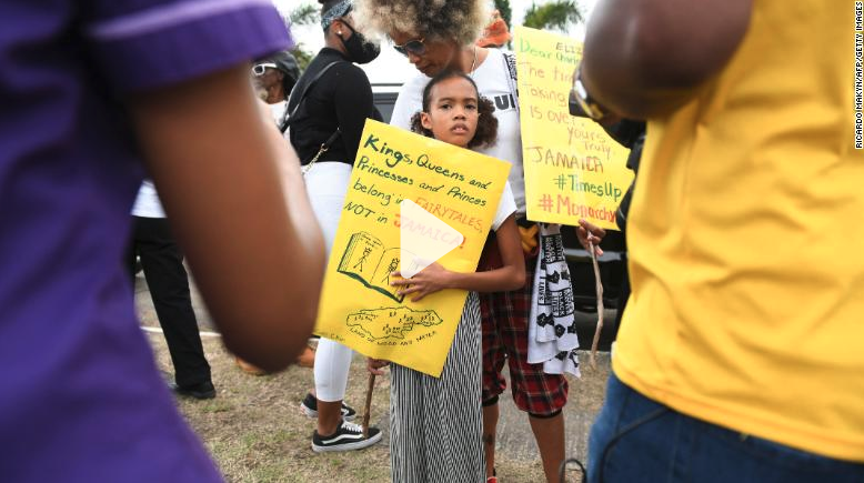 A girl holds a poster during a protest against the royal visit in the Caribbean this week.