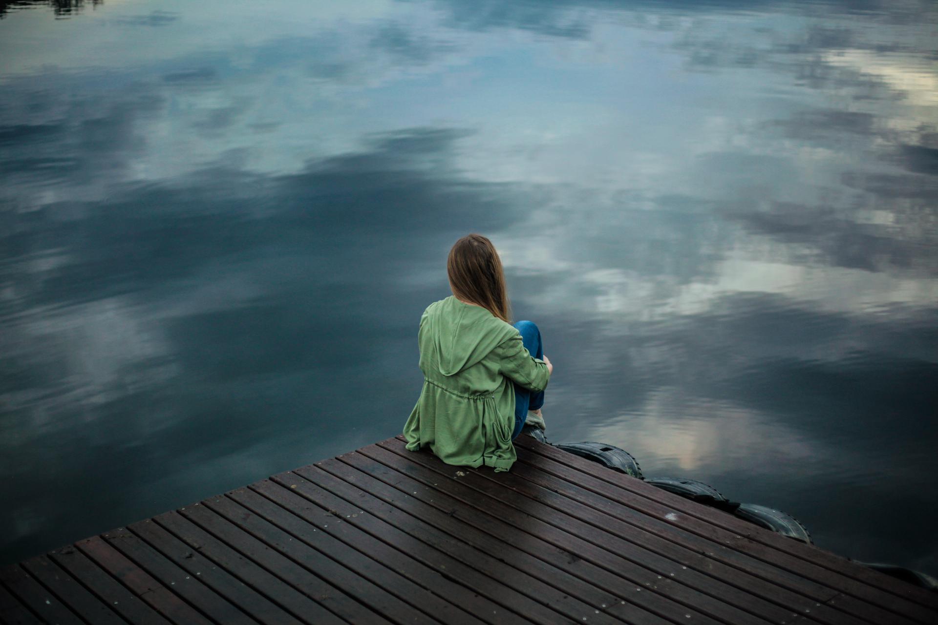 Image of person sitting alone on a dock. Credit: Pexels