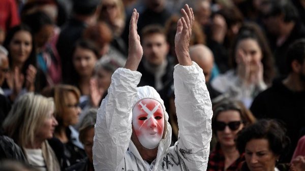 A protester wearing a mask depicting syringes applauds in Geneva, Switzerland, on October 9, 2021.