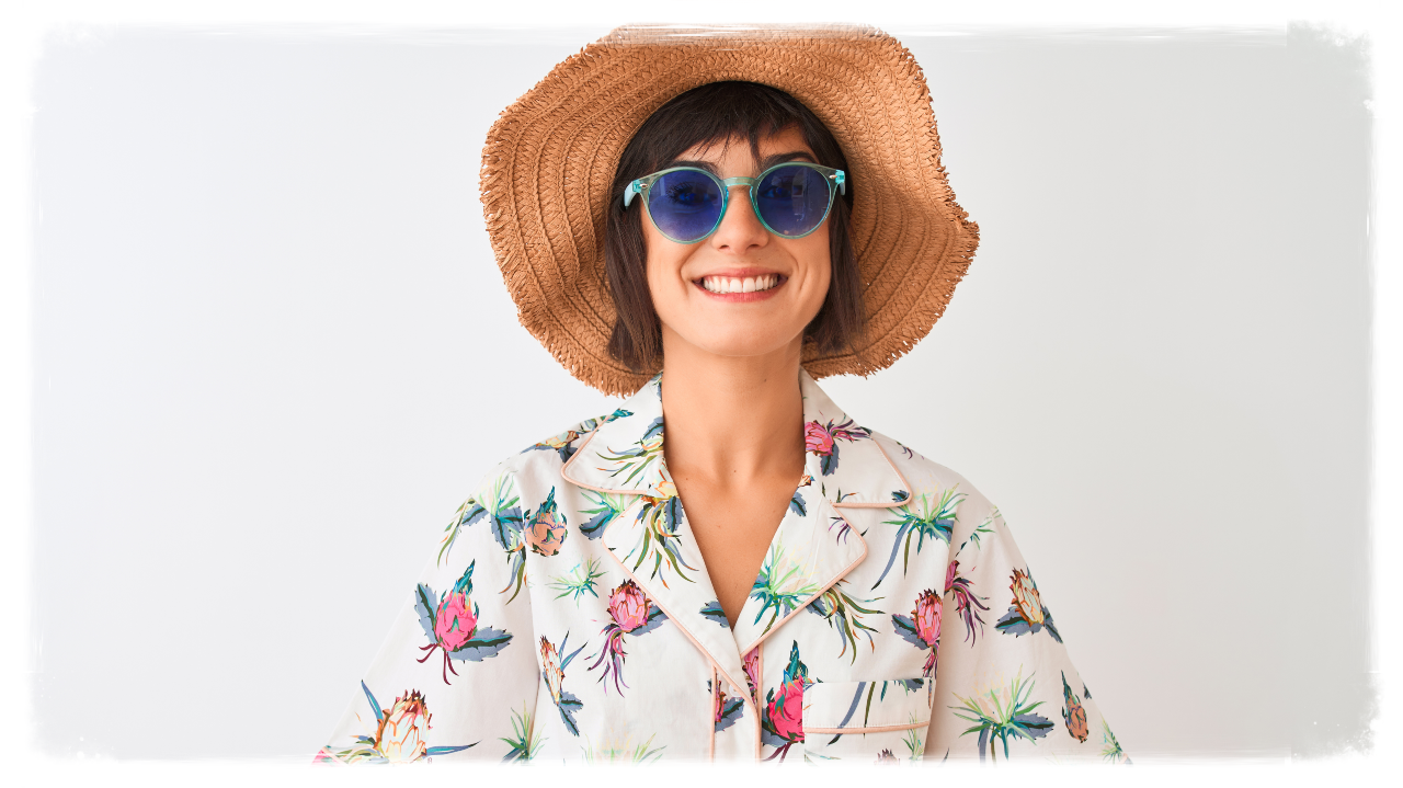 Woman wearing summer hat shirt and sunglasses over isolated white background with a happy face standing and smiling 