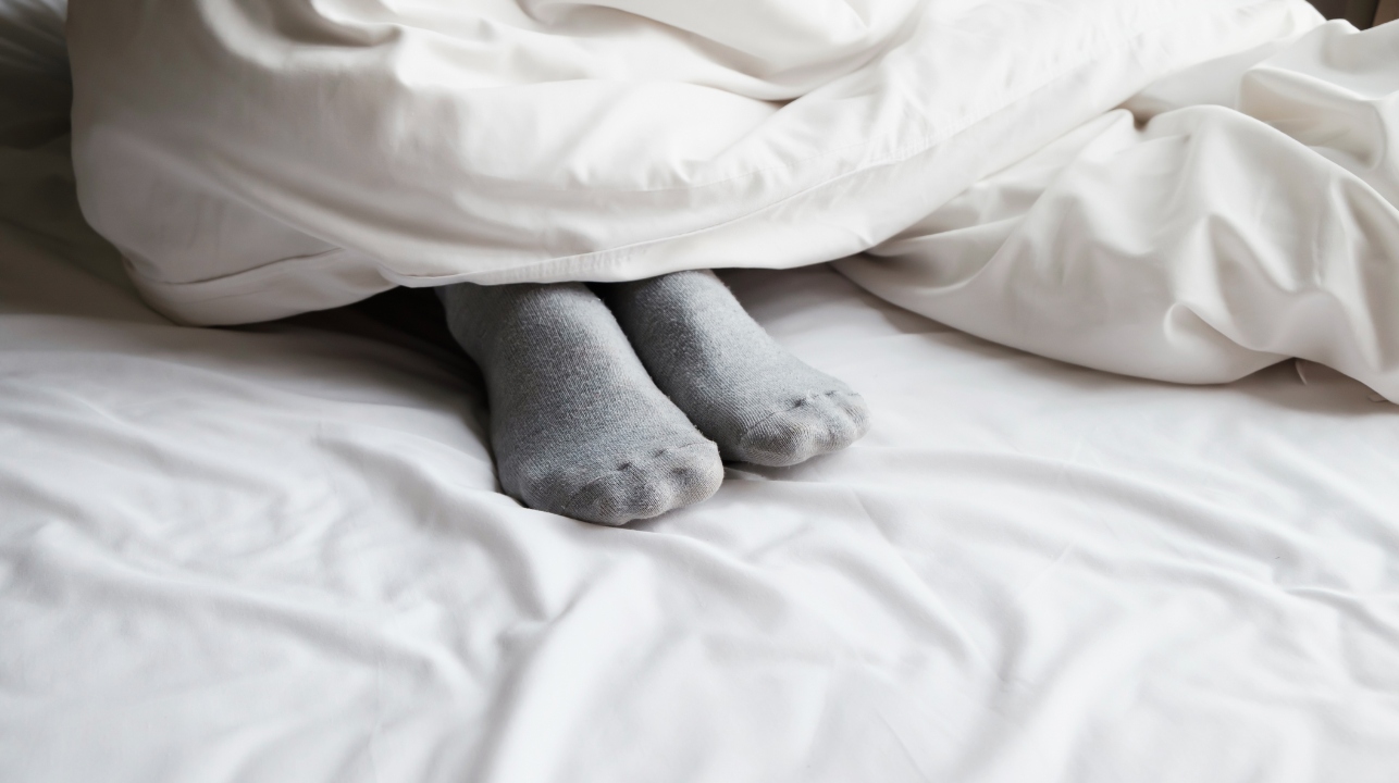 Feet with socks poking out under a comforter