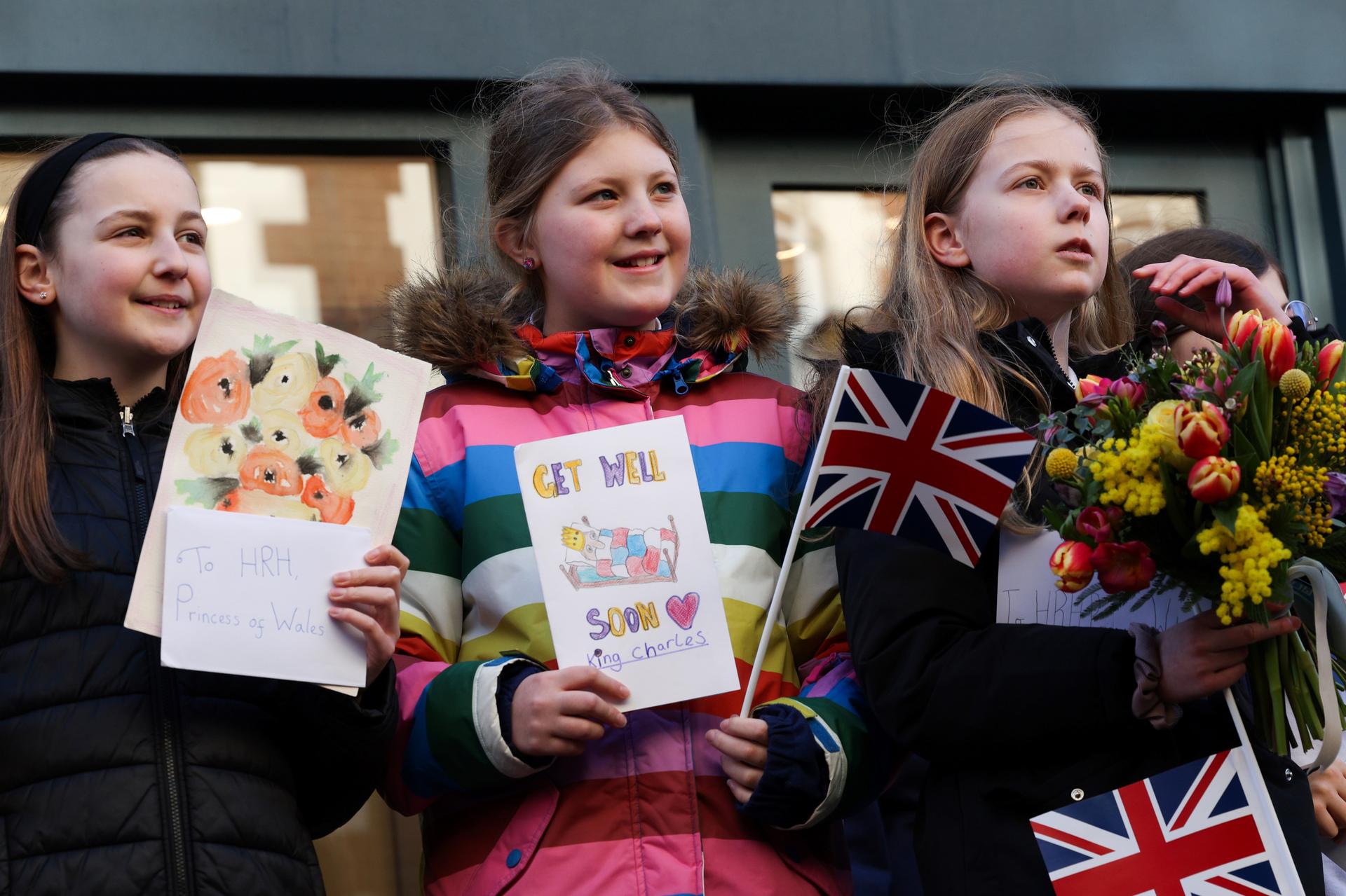 A group of girls hold get well cards for Britain's King Charles III as they wait to greet Queen Camilla during her visit to Swindon, England.