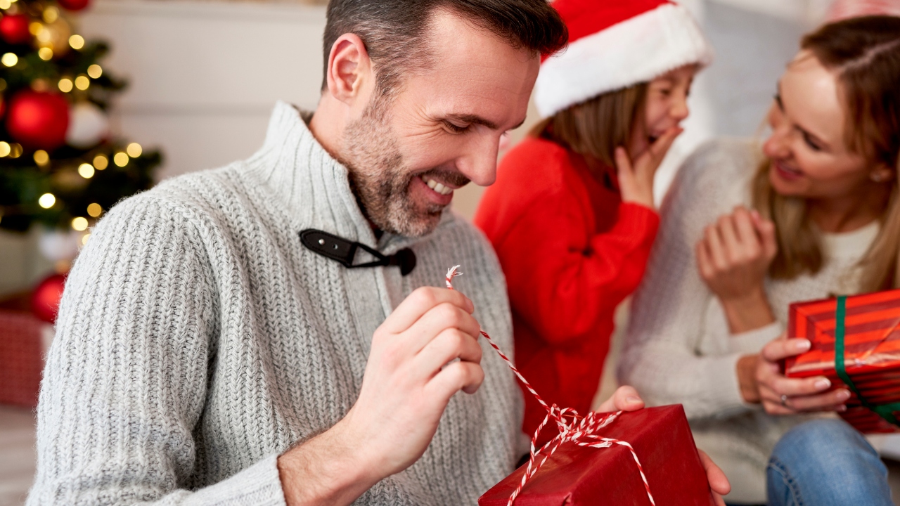 Man smiling while opening a wrapped gift