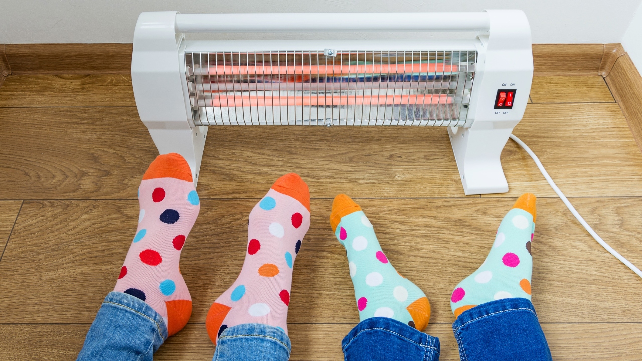 Two pairs of feet in socks in front of a space heater