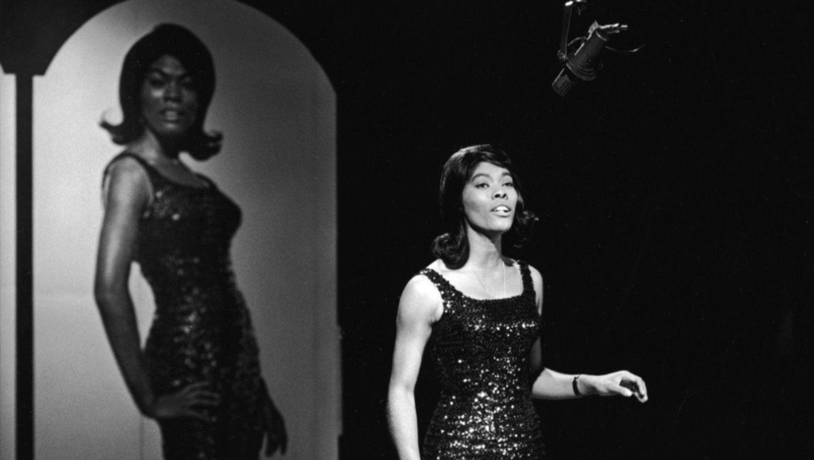 Warwick sings in front of a poster in 1965. (Source: NBC Television/Getty Images/Hulton Archive)