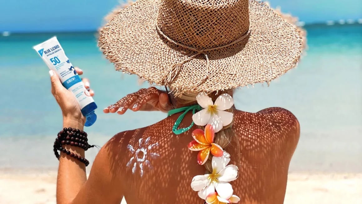 Pereson applying sunscreen to her back