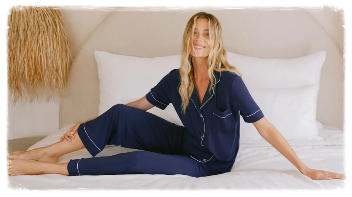 Woman sitting on bed wearing blue pajamas