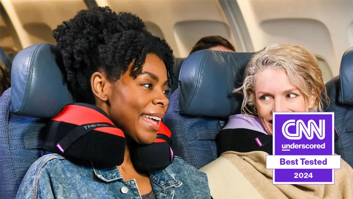 Two women on a plane wearing travel pillows