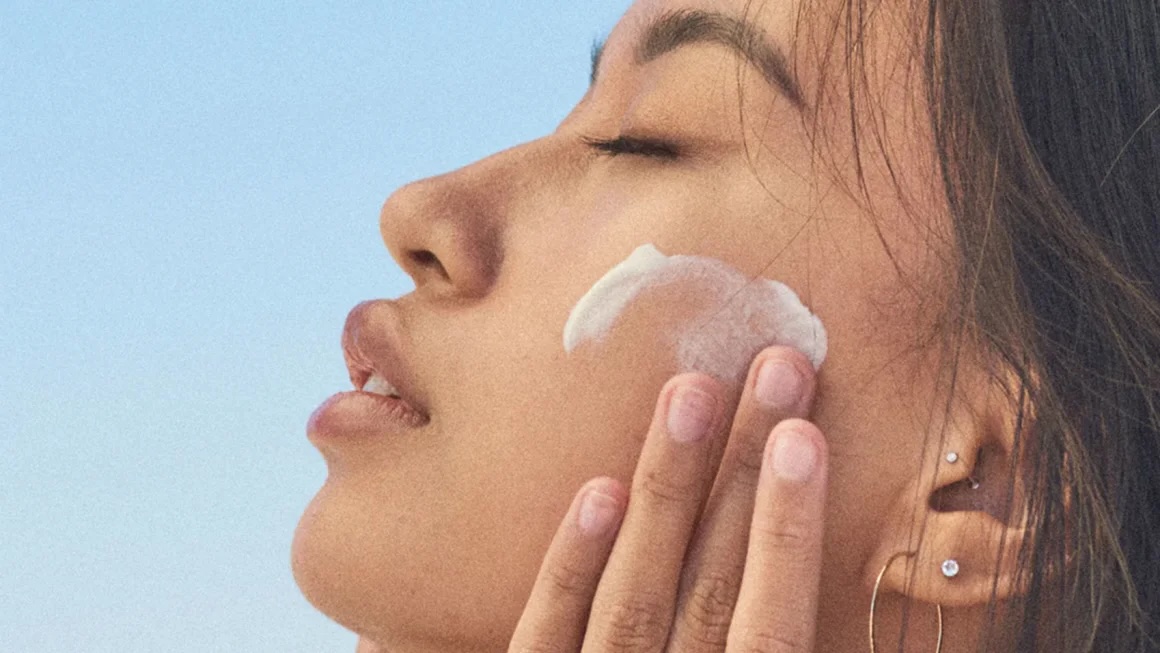 An up close shot of a woman putting on sunscreen on her face