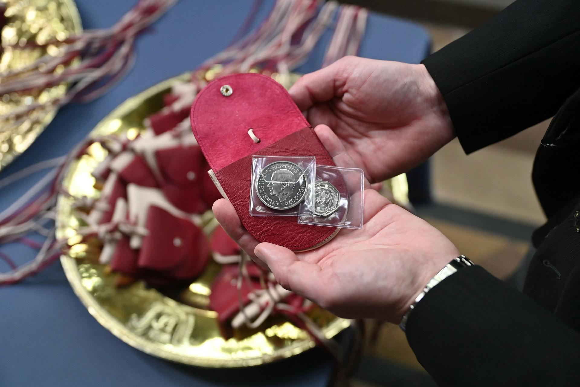 The red purses contains a £5 coin which features the image of a Tudor Dragon, and a 50p coin commemorating the RNLI as Britain's Queen Camilla distributes the Maundy Money, in Worcester Cathedral on March 28, 2024 in Worcester, England.