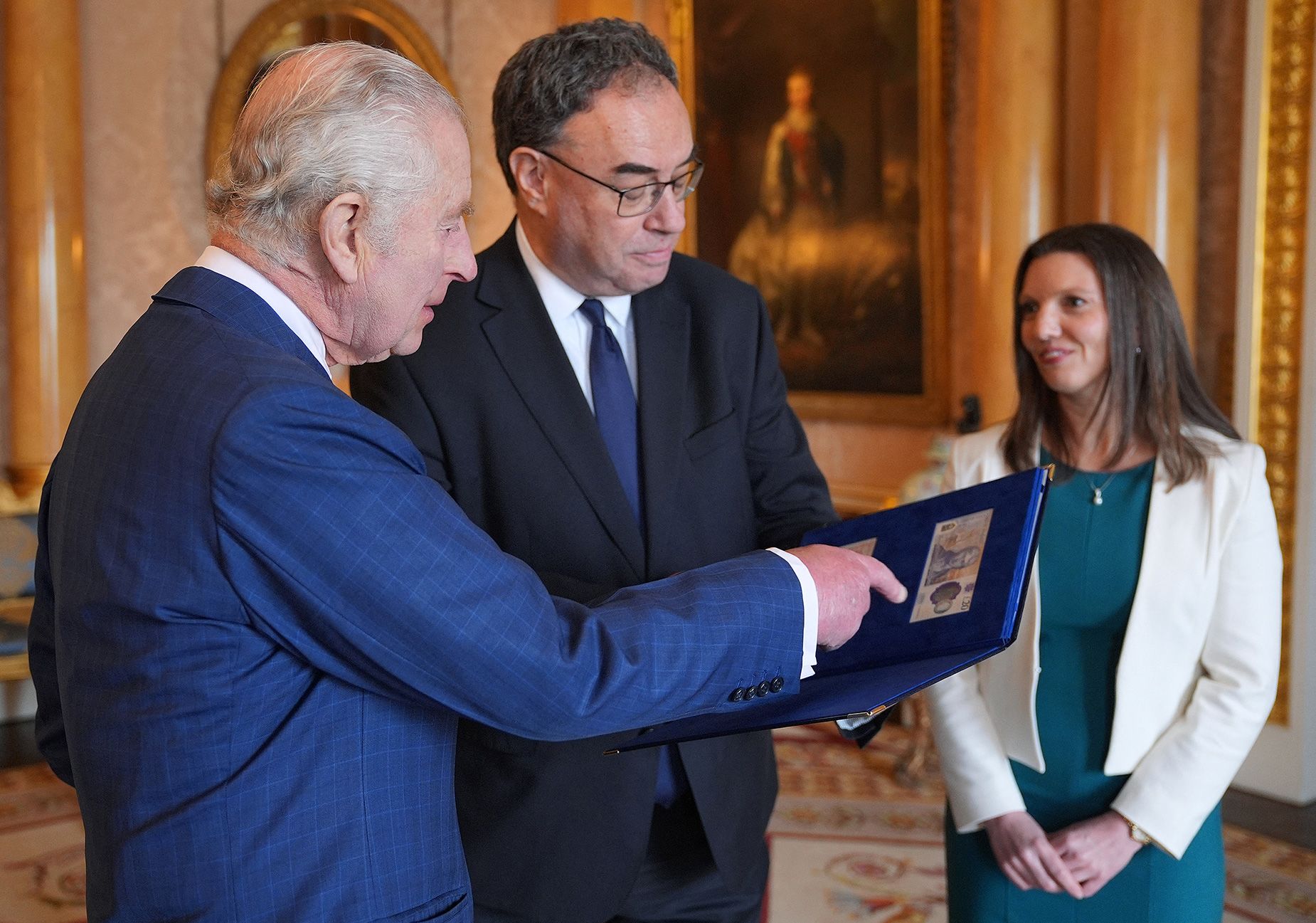 The King is presented with the first bank notes featuring his portrait by Bank of England Governor Andrew Bailey and Chief Cashier Sarah John.