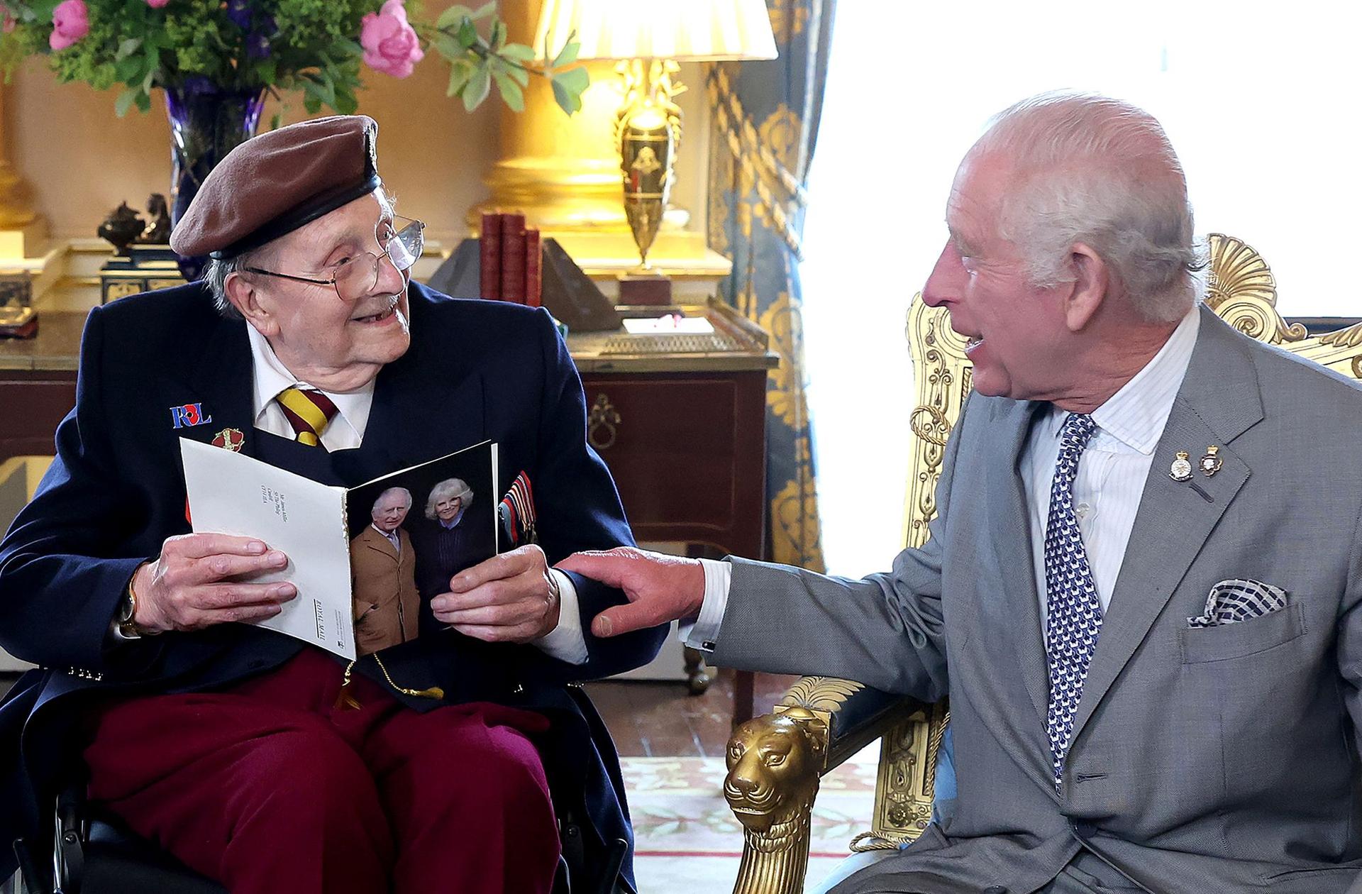 King Charles III presents D-Day veteran Jim Miller with a card to mark his 100th birthday during a visit at Buckingham Palace on May 22.