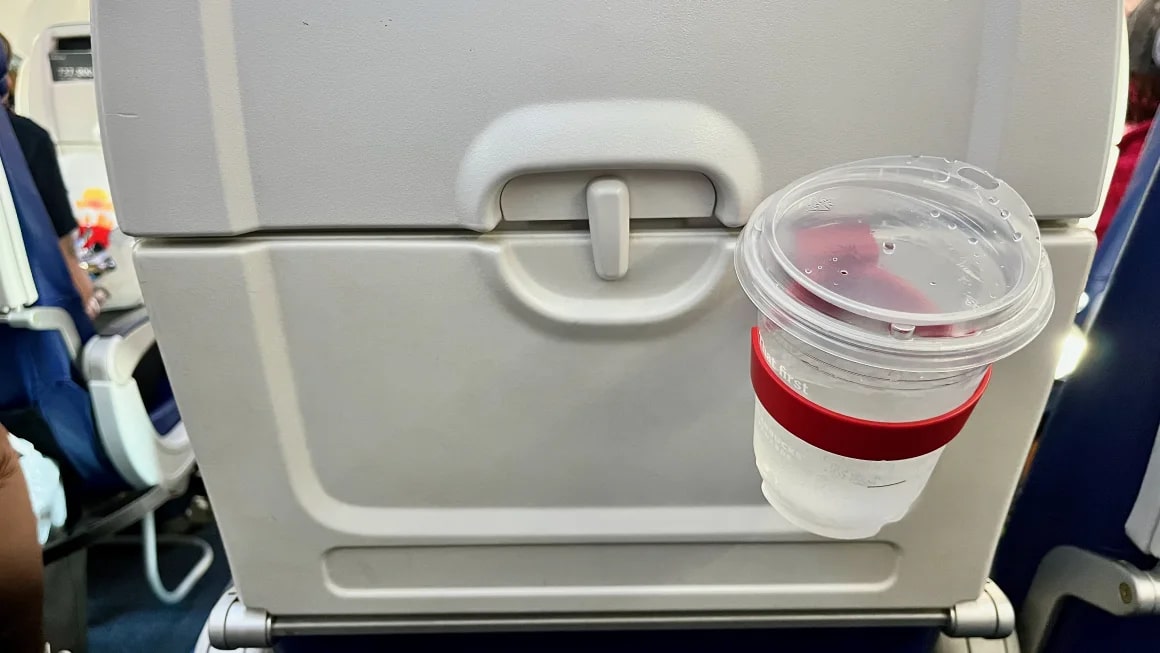 Red cup holder on the back of a plane seat