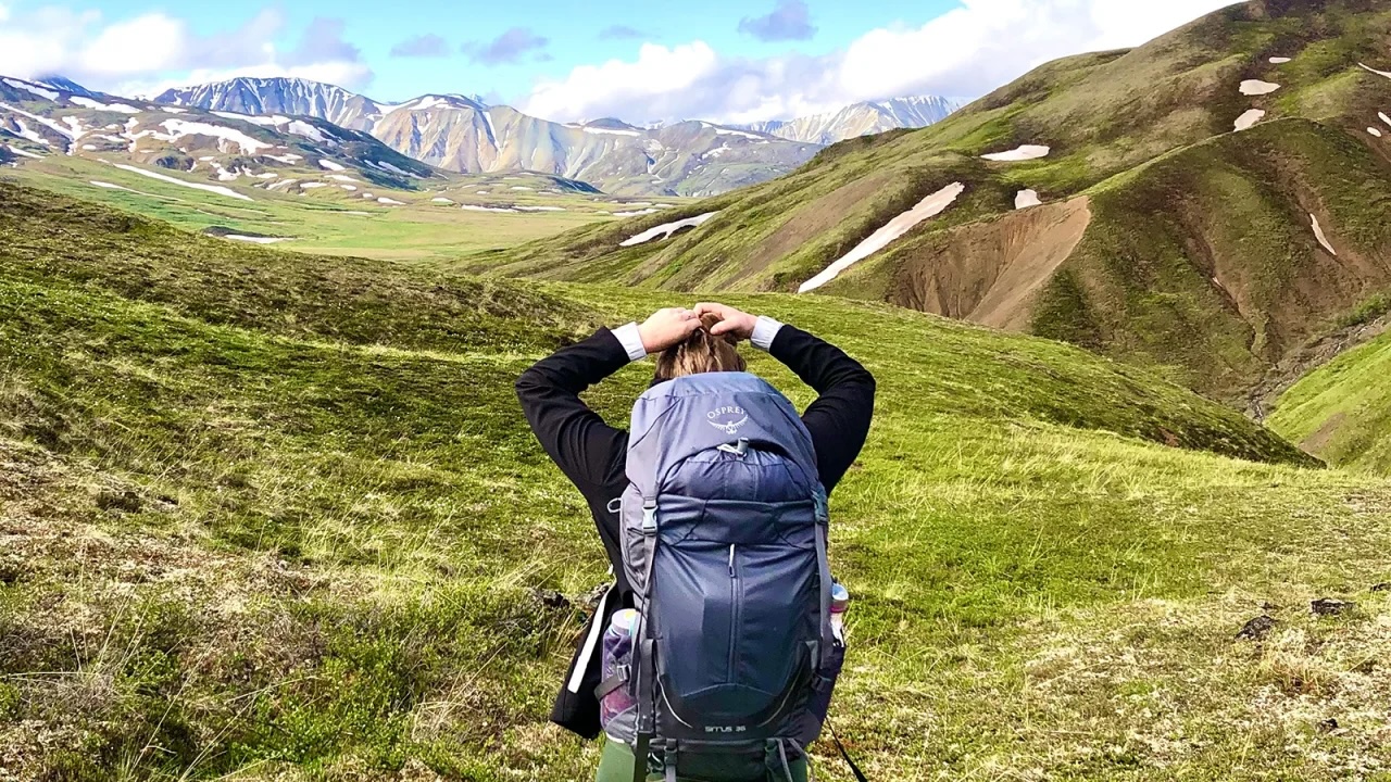 Woman wearing hiking backpack with view of mountains in the background