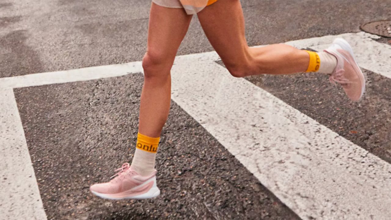 Lower half of a person's body wearing running shoes on a street crosswalk.