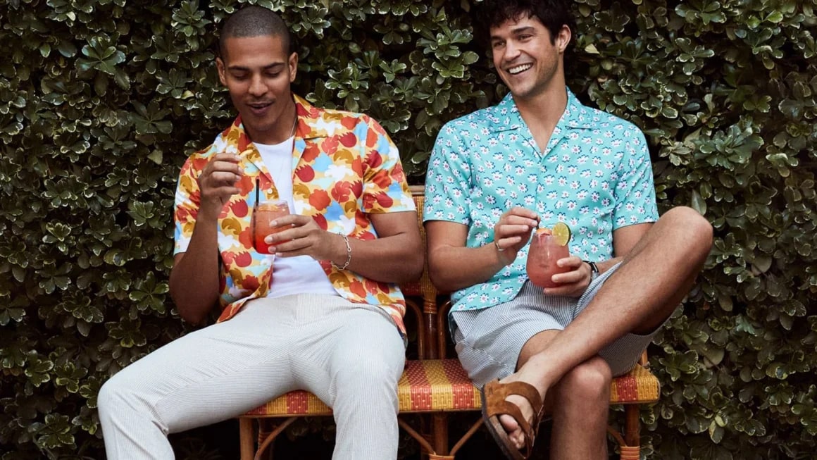 Two men sitting on a bench while wearing bright button up shirts