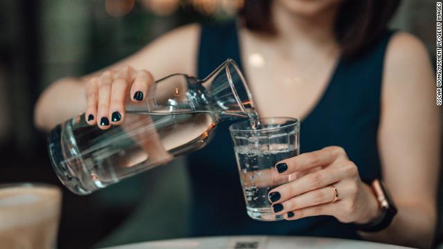 A person pours water into a glass