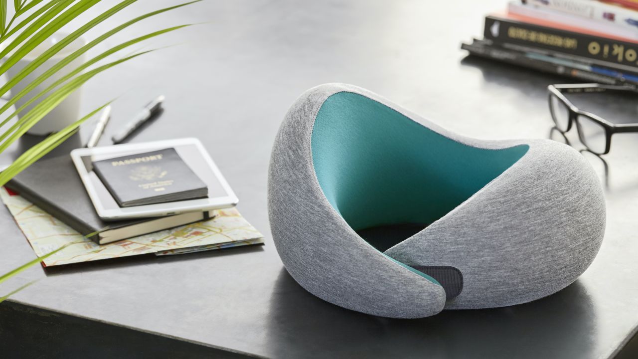 Gray and teal Ostrichpillow Go Neck Pillow atop a desk.