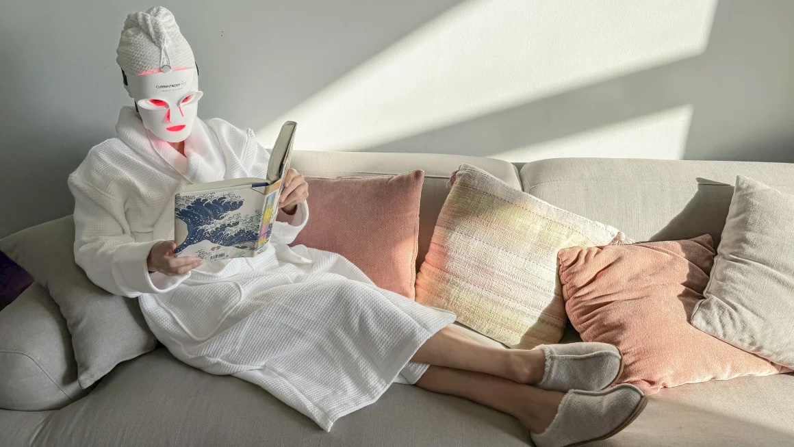 woman sitting on couch with robe and face mask