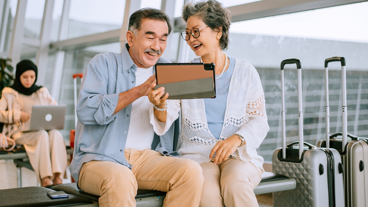 Two people at an airport looking at a tablet