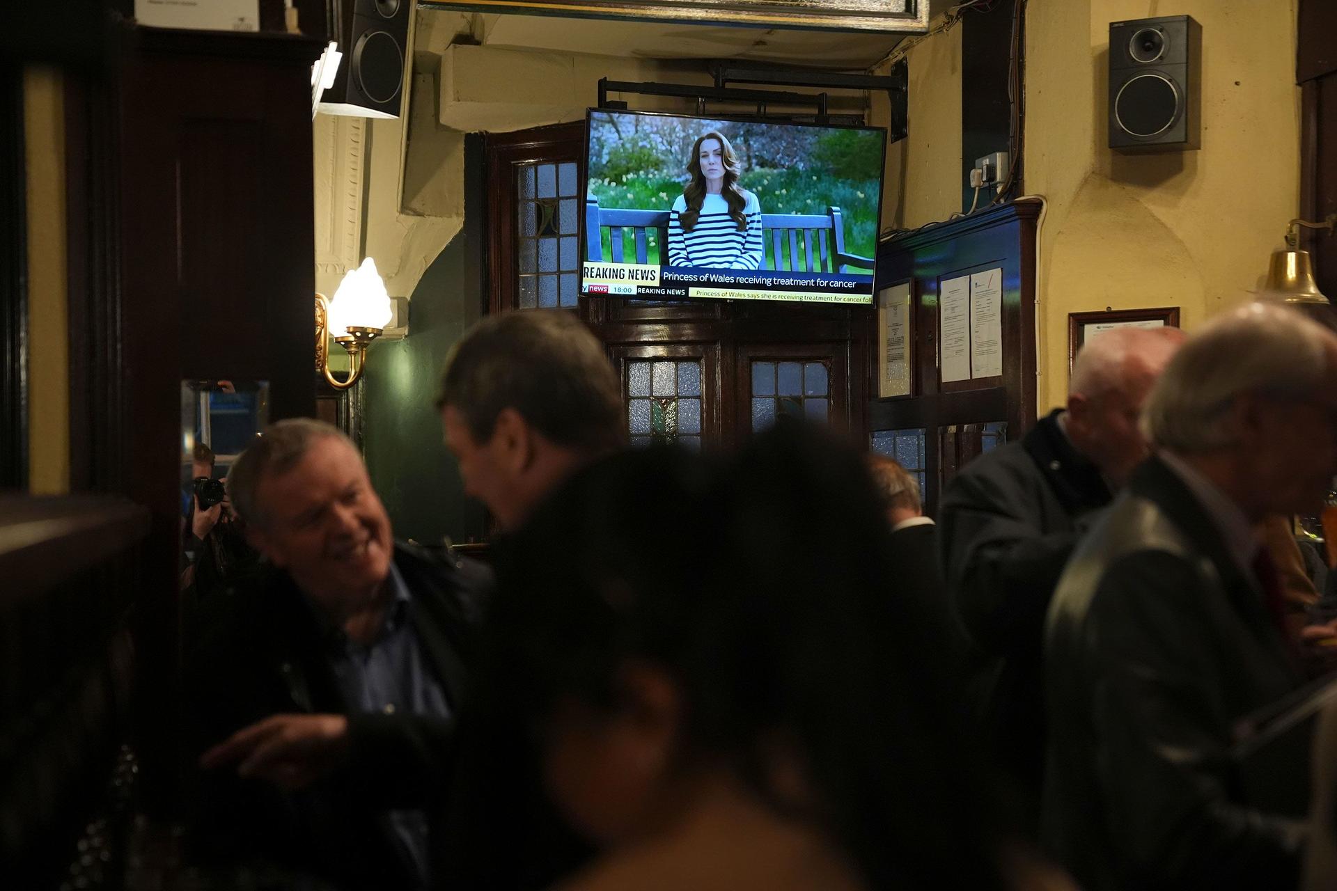 People watch a broadcast in a London pub  following the announcement by the Princess of Wales that she is undergoing chemotherapy treatment for cancer.